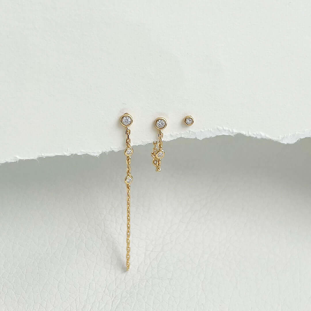 Libi Earrings Set featuring gold minimalist studs with sparkling accents on a textured background.