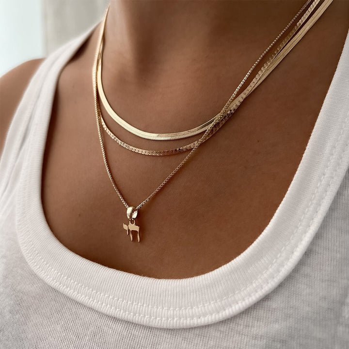 Close-up of a Chai Necklace worn with layered gold chains, symbolizing life and elegance.