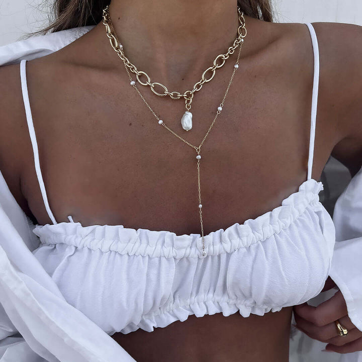 Tulum Necklace displayed on model, featuring pearl lariat chain and layered with gold accents, perfect for a beach getaway.