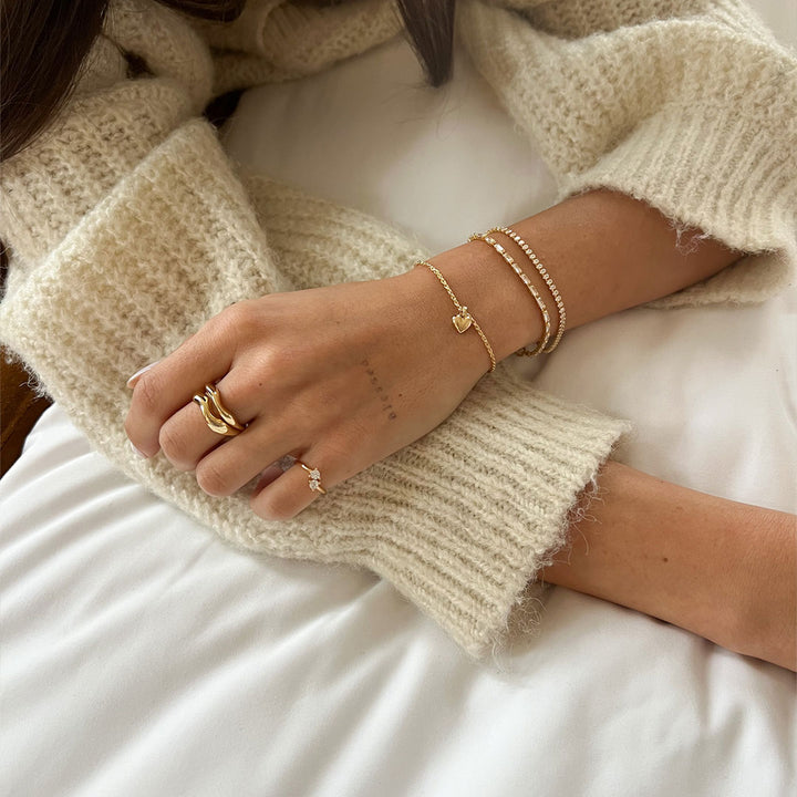Mali Heart Bracelet worn on a wrist with a cozy knit sweater, showcasing its delicate design and charm.