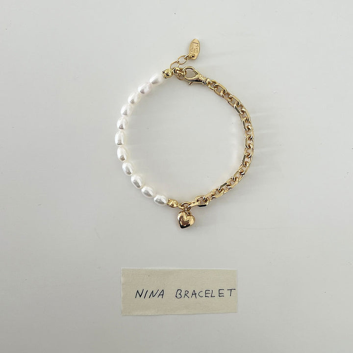 Nina Bracelet featuring a delicate chain, natural pearls, and a bold heart charm for a stylish look.