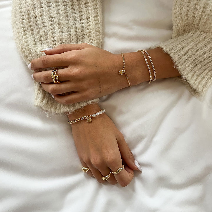Mali Heart Bracelet with a delicate braided chain and heart charm, styled with other wrist accessories.