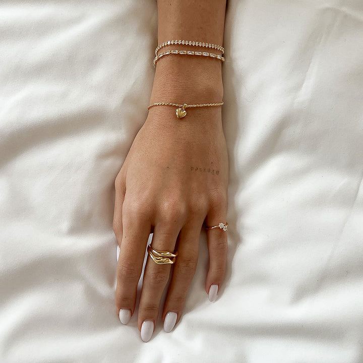 Mali Heart Bracelet showcased on a hand with other delicate jewelry and a soft background.