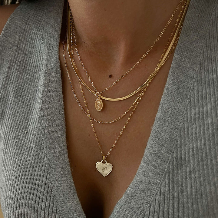 Eva Necklace stacked with other gold necklaces, featuring a heart pendant and oval charm, showcasing elegant layering.