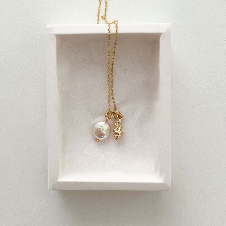 Maya Necklace featuring a delicate chain with seashell charm and freshwater pearl pendant in a gift box.