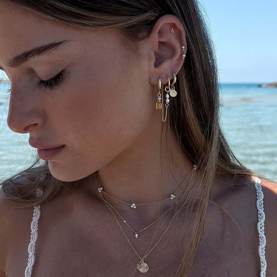 Close-up of a model wearing the Reef Earrings Set, showcasing ocean-inspired hoops, shells, and pearls.