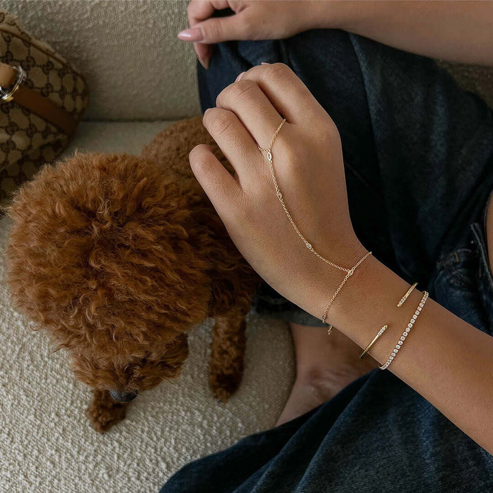 A hand adorned with the Sol Hand Chain Bracelet, featuring a delicate chain and sparkling Crystal Stone.