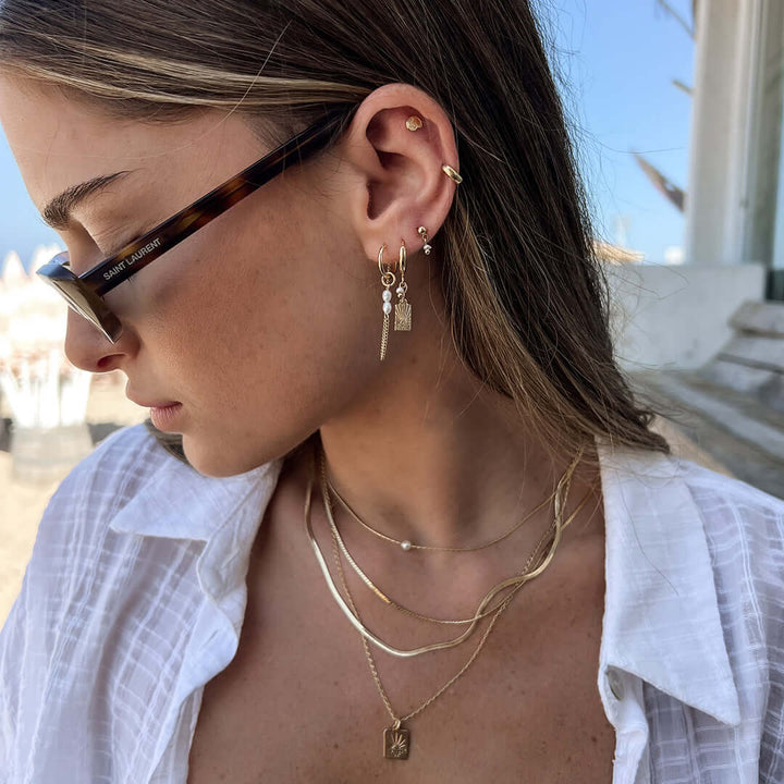 Model wearing Sunny Earrings, showcasing their dainty drop design and stylish accessories in sunlight.