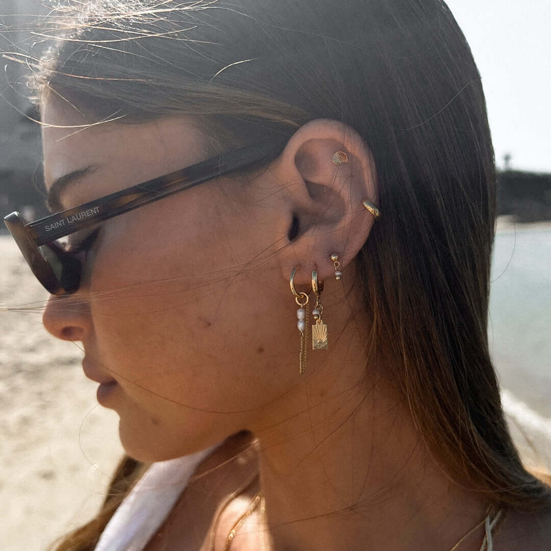Close-up of a woman wearing the Sunset Earrings Set featuring an engraved sunset charm and chic design.