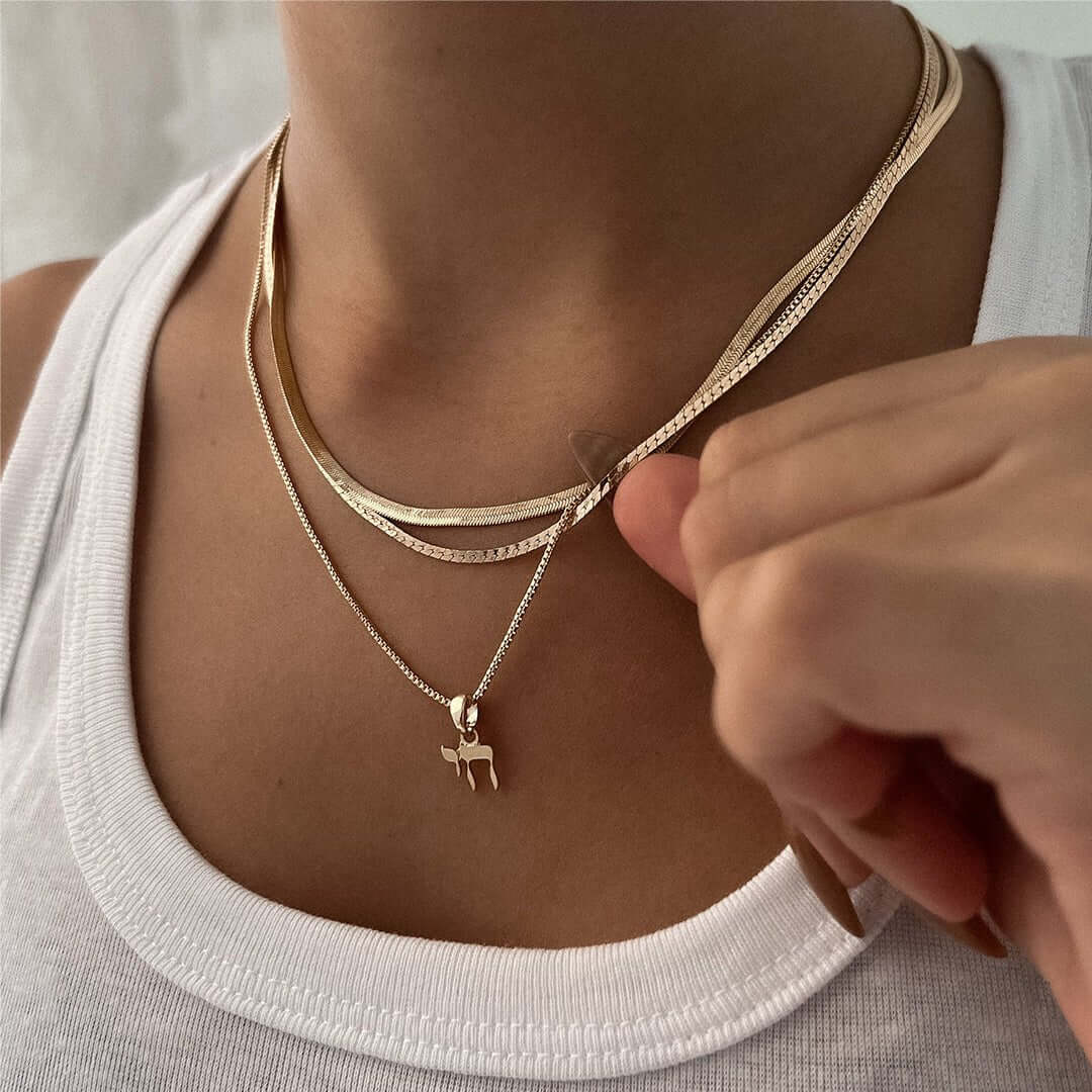 Chai Necklace showcasing a delicate 'Chai' pendant worn with layered gold and silver chains, symbolizing life and strength.