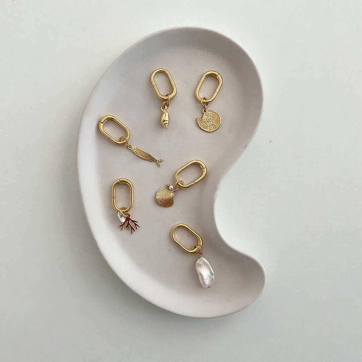 Pearl Charm collection displayed on a ceramic dish, showcasing unique gold charms for personal accessories.
