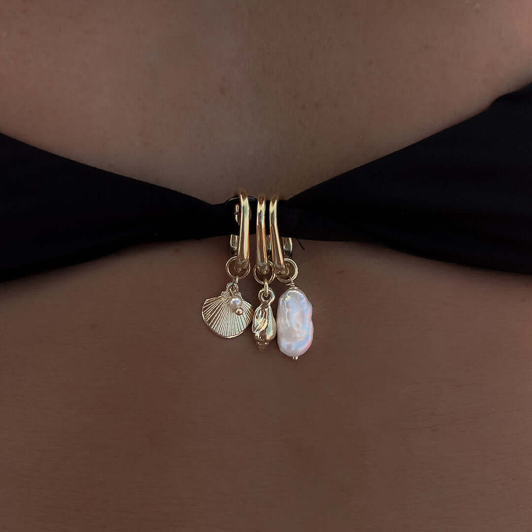 Close-up of a Pearl Charm attached to a swimsuit, featuring gold accents and additional sea-themed charms.