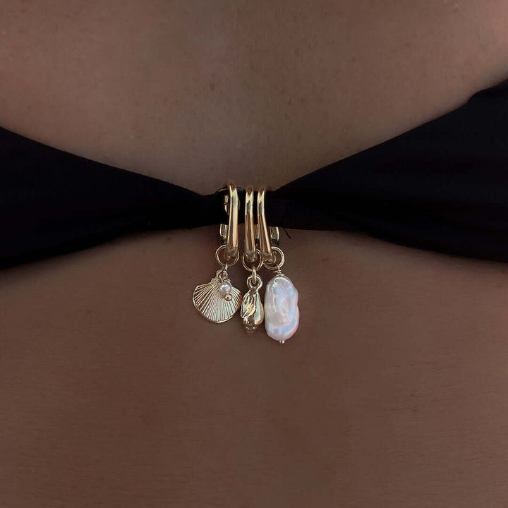 Close-up of a Pearl Charm attached to a swimsuit, featuring gold accents and additional sea-themed charms.