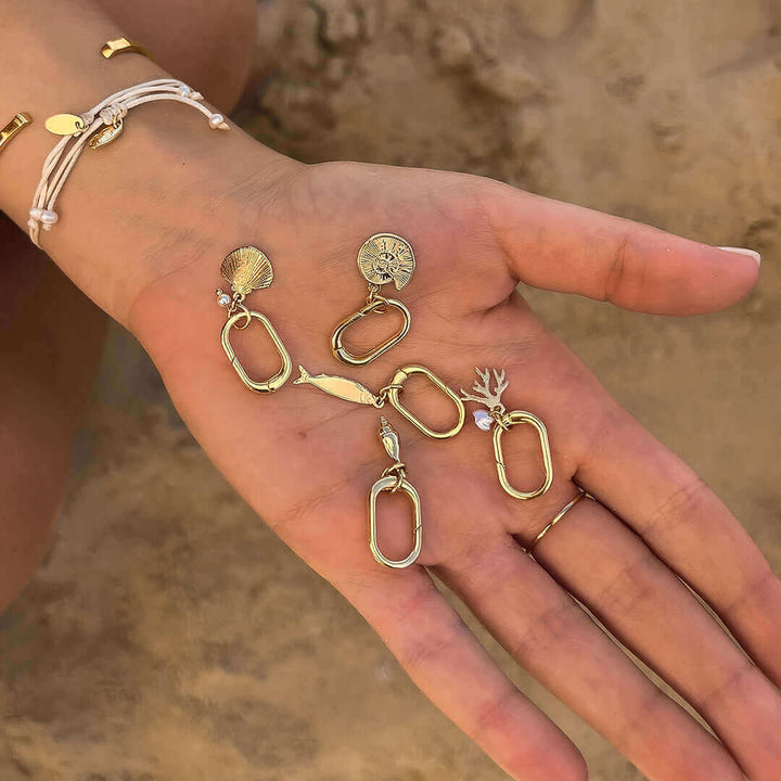 Hand holding various golden charms including Pearl Charm, perfect for adding personal touches to accessories.