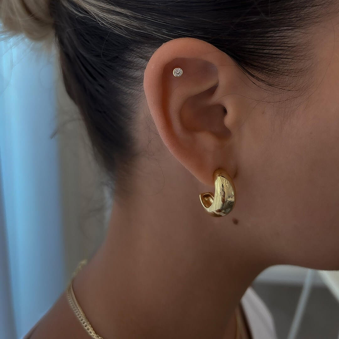 Chris Earrings styled in a model's ear, showcasing classic round crystal studs with delicate sparkle.