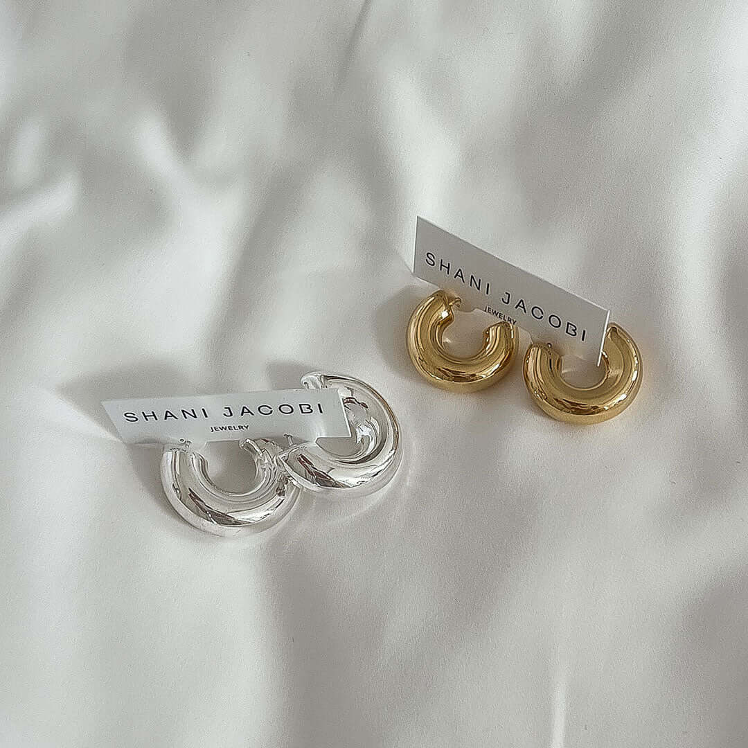 Mango Earrings in silver and gold displayed on a soft white background with branded labels.