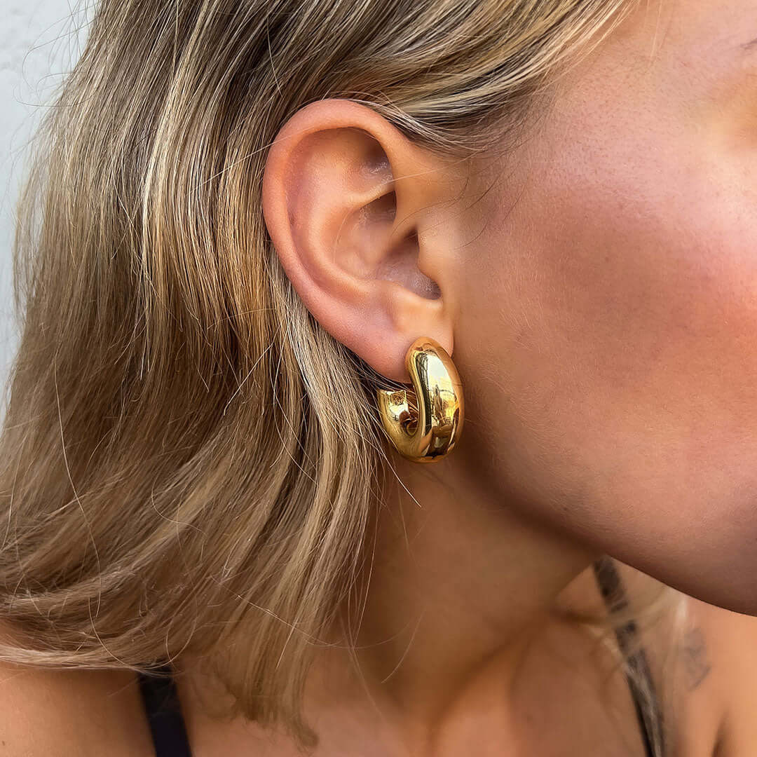 Woman wearing Mango Earrings featuring a trendy gold hoop design.