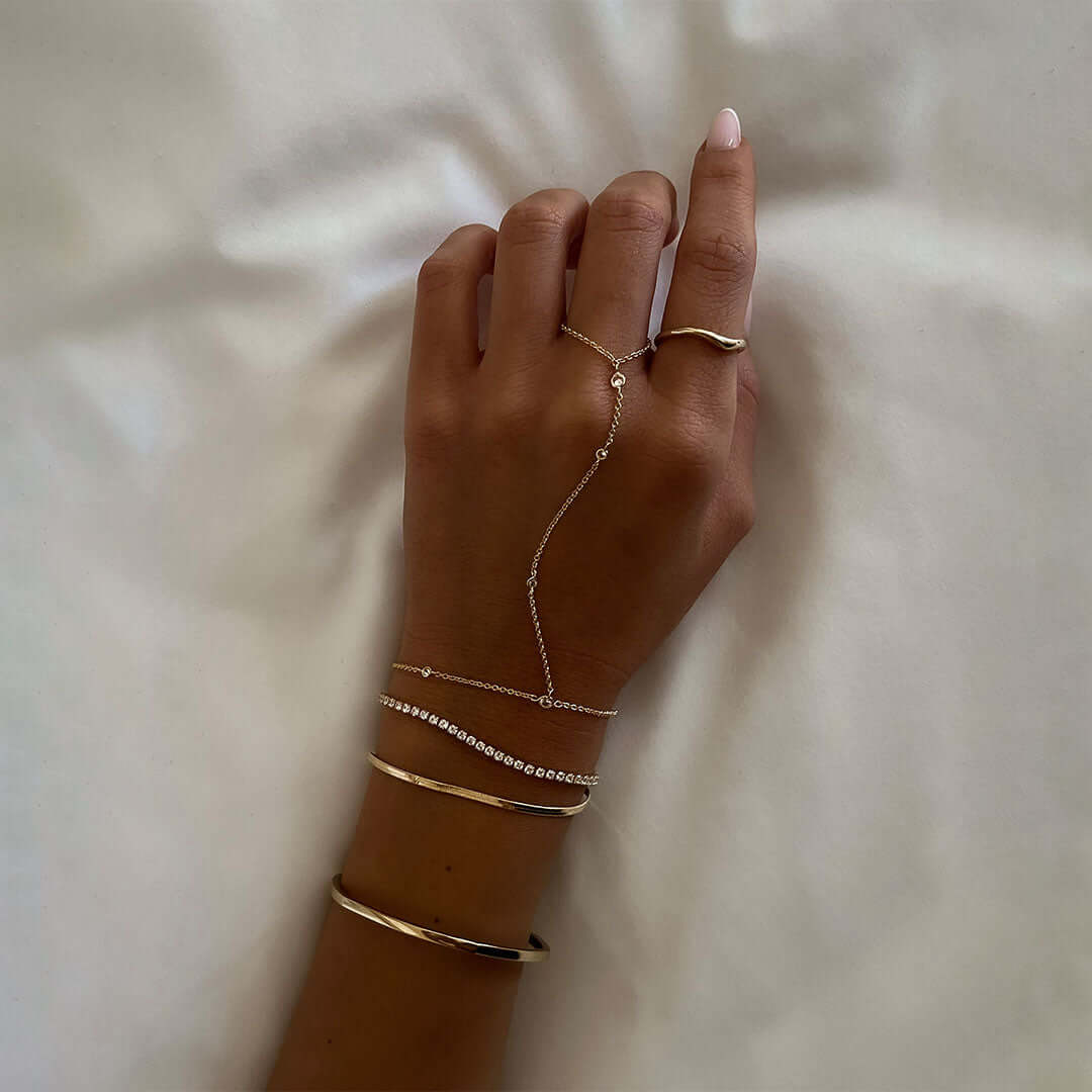 Elegant hand adorned with multiple bracelets including a 14K gold plated tennis bracelet by Shani Jacobi.