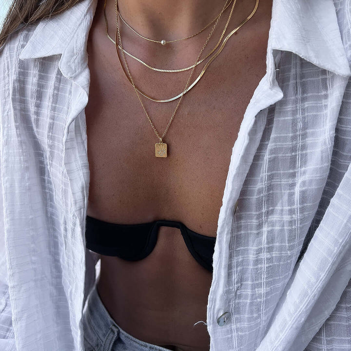 Wearing the Double Sunset Necklace with layered gold chains, showcasing its elegant sunset-inspired pendant.